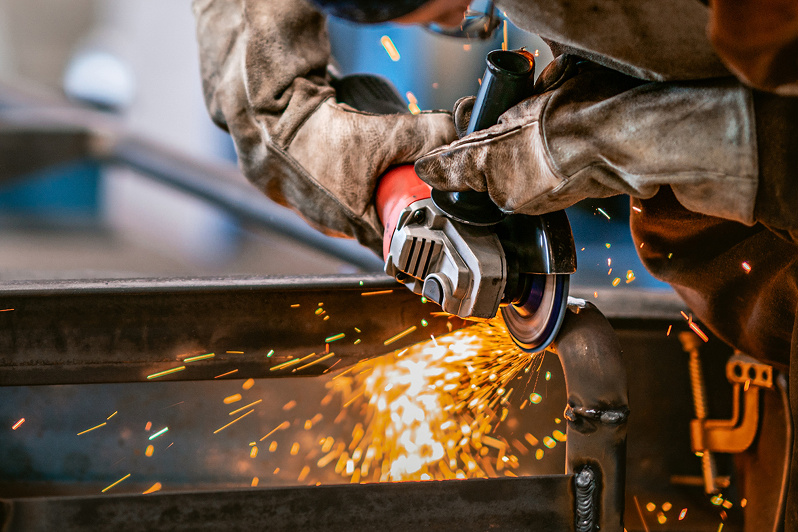 Heavy industry worker grinds steel with an angle grinder,sparks flying,close up.